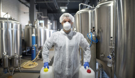 Industrial worker holding plastic cans with chemicals in production plant.